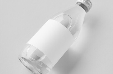 Small water bottle mockup with blank label, clear glass, closeup