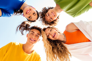 Cheerful group of teenagers enjoying outdoor gathering together in bright daylight showcasing...