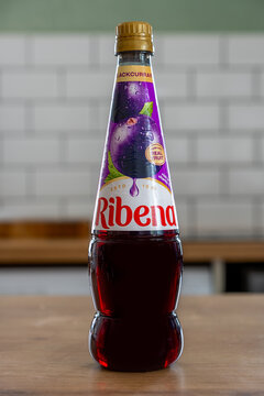 A bottle of Ribena blackcurrant juice cordial drink with a rich, deep color on a wooden table.