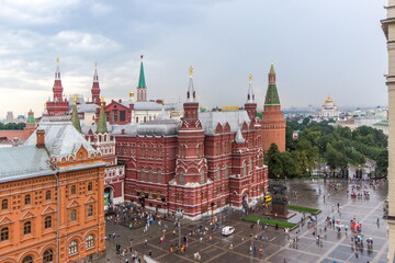 Fototapeta premium Red Square in Moscow showcases its stunning historic buildings under a cloudy sky. Tourists roam around while admire the unique architecture that defines this iconic location