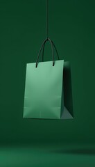 Emerald green shopping bag gracefully suspended from a thin string against a dark green backdrop