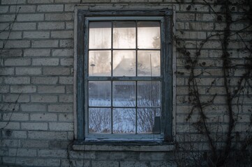 Fototapeta premium A weathered window covered in frost and snow in a deserted structure.