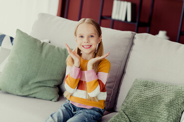 Happy young girl enjoying leisure time indoors on a cozy sofa in a cheerful and lively home...