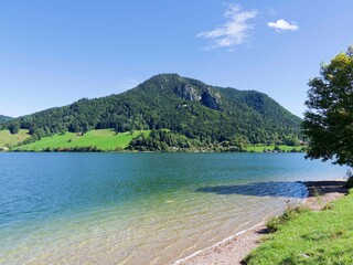 Lake Schliersee in Upper Bavaria, Germany. A small beach on the lake's southern shore offers a view of the rocky, wooded slopes of the Hirschgröhrkopf.
