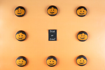 Flat lay of halloween pumpkin and chocolate cookies arranged in a square around a 