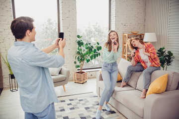 Funny young friends enjoying quality time together at home singing and having fun in a cozy, stylish living room setting