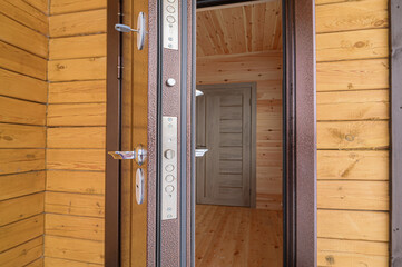 Open metal door revealing a wooden interior. The door hardware is visible. Wooden walls and floors...