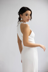 Beautiful young woman in stylish white dress posing confidently indoors