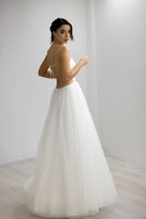 Elegant young model wearing open back wedding dress posing indoors