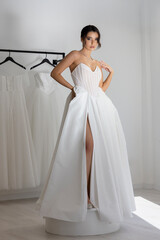 Fashion model in modern strapless wedding dress with slit posing indoors
