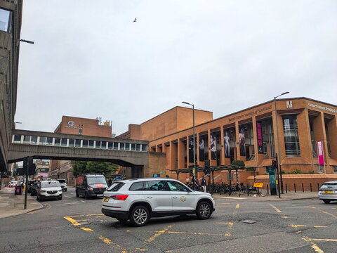 Cars navigate a Glasgow city junction past the modern Royal Conservatoire of Scotland building