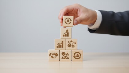Obraz premium Building the Path to Progress: A hand meticulously places a wooden block, symbolizing strategic growth and progress, atop a pyramid of interconnected business icons.