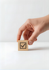 Hand placing the final wooden cube with a checkmark symbol, showing success and accomplishment, minimal clean background, corporate achievement concept