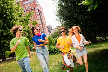Fototapeta premium Happy group of diverse young friends enjoying outdoor activities on a sunny day in the city park together