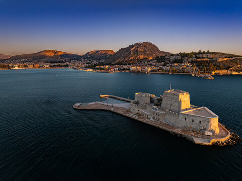 Aerial view of the formidable Bourtzi Castle standing proud against the deep blue sea and the sun-kissed hills of Nafplion, Argolis, Greece.