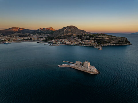 Aerial view of the formidable Bourtzi castle emerging from the tranquil waters, guarding the historic city and the towering Palamidi fortress, Nafplion, Argolis, Greece.