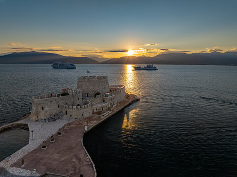 Aerial view of the Bourtzi Castle standing guard in the tranquil waters, bathed in the warm glow of the setting sun, Nafplion, Argolis, Greece.