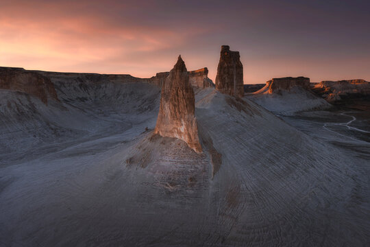 Aerial view of stark white rock formations sculpted by time and weather under a fiery sunset sky, Boszhira, Mangystau Region, Kazakhstan.