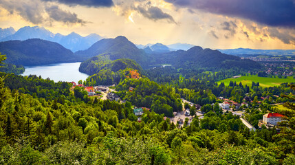 Fussen, Bavaria, Germany. Panoramic view at Castle of Hohenschwangau Village, famous landmark. Alpsee Alpine lake and Alps Mountains on horizon. Ostallgau district.