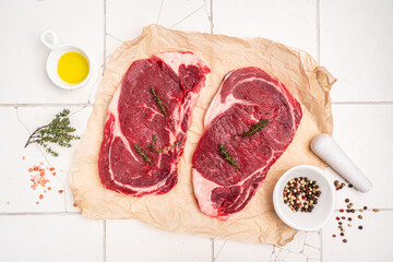 Raw fresh beef steak on a paper with spices on a white background. Top view with copy space. High quality photo
