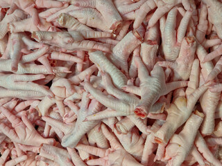 Close-up of a large pile of raw, pale pink-to-white chicken feet. 