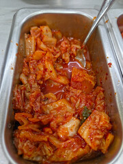 A vertical close-up shot of a metal serving tray filled with Kimchi, a traditional Korean side dish. 