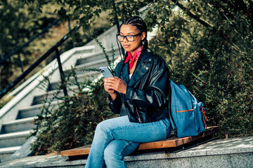 Lovely woman wearing casual attire exploring city outdoors on a sunny day while using smartphone and enjoying lifestyle