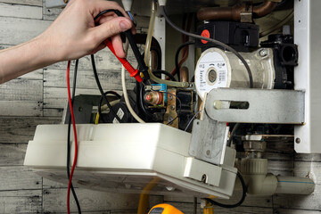 A young man is repairing an electric water heating boiler.