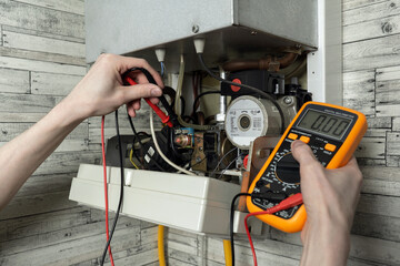A young man is repairing an electric water heating boiler.