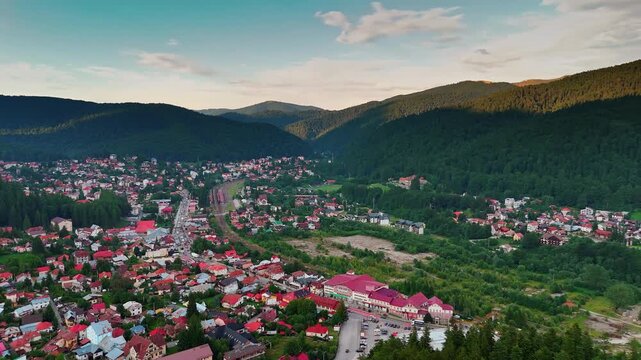 Footage above the cozy residential area in the green mountains. Lively town of Busteni, Romania from drone.