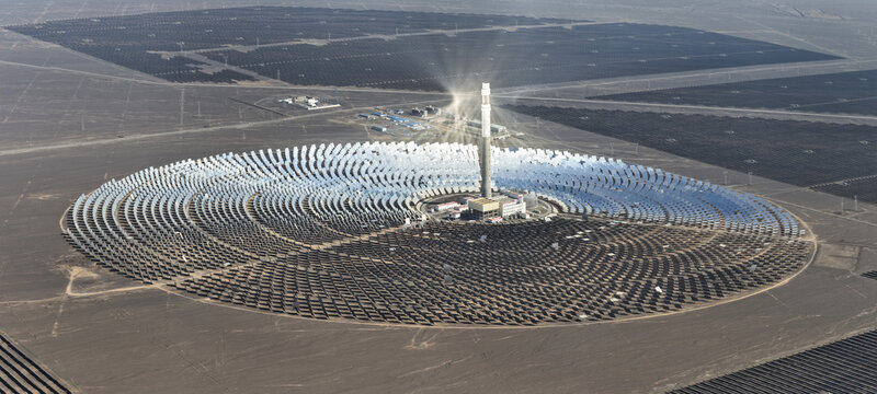 Aerial view of a solar power plant with a central tower reflecting sunlight in a circular pattern, Turpan, Xinjiang, China.