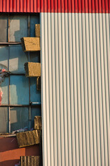 Zbliżenie na elewację budynku przemysłowego, ukazujące falisty pas blachy z metalu pod którą znajduje się ocieplenie z wełny mineralnej. © Pol Badger