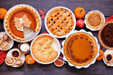 Homemade autumn pie table scene. Overhead view on a dark wood background. Variety of apple, pumpkin...
