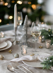 Elegant Christmas table setting with wine glasses, napkin, ornaments, and candlelight for holiday dining