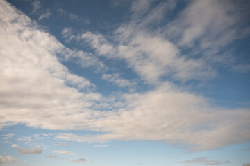 Obraz premium An expansive blue sky is filled with streaks of white and light grey clouds in a dynamic, sweeping pattern, suggesting movement and high altitude.