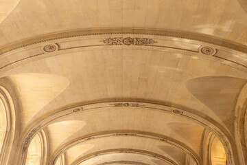 Architectural ceiling design featuring intricate moldings and arches, showcasing elegant craftsmanship and historical aesthetics in a grand interior space with natural light