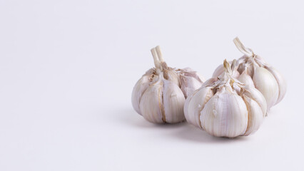 Three fresh garlic bulbs on clean white background, perfect for cooking, spices, healthy food, natural ingredient, freshness, and copy space design.
