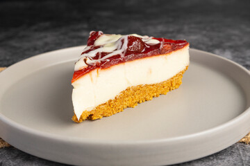 Cheesecake slice with fruit sauce and glaze on ceramic plate over burlap, top view food photography for dessert presentation and culinary design