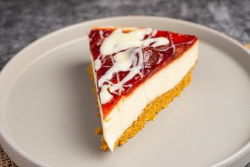 Cheesecake slice with fruit sauce and glaze on ceramic plate over burlap, top view food photography for dessert presentation and culinary design