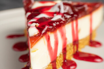 Cheesecake slice with fruit sauce and glaze on ceramic plate over burlap, top view food photography for dessert presentation and culinary design