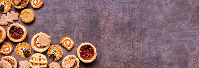 Thanksgiving or autumn dessert corner border. Overhead view against a dark banner background. Pumpkin, apple and pecan mini pies, turkey, leaf and snickerdoodle cookies, pumpkin rolls.