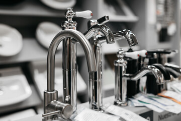 Water taps of different types and shapes on the counter in the store. Retail trade in sanitary ware.