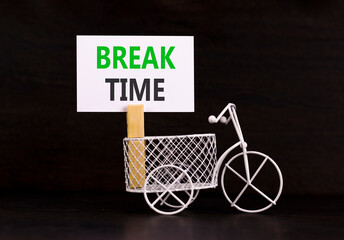 Break time symbol. Concept word Break time on beautiful white paper. Beautiful wooden clothespin. Beautiful black background. Miniature white bicycle. Business break time concept. Copy space.
