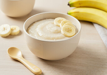 Baby porridge with banana slices in bowl for infant nutrition