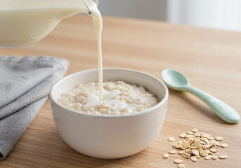 Baby porridge with milk in white bowl