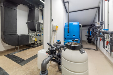 Inside a water treatment plant, various pieces of equipment are arranged, including large tanks,...