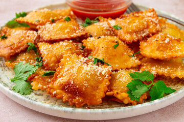 fried ravioli with parmesan cheese, served with red sauce and garnished with herbs, on a light background, no people,