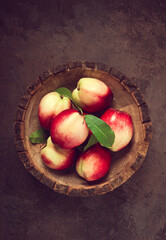 ripe nectarine, in a wooden plate, brown background, top view, no people,