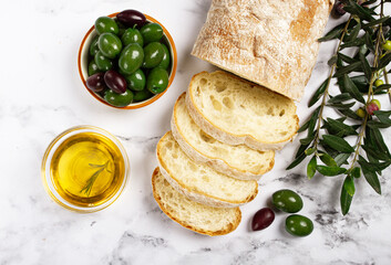appetizer, sliced ciabatta bread, with olive oil, green olives, Chalkidiki olives, classic Green green olive, on a marble table, top view, no people,