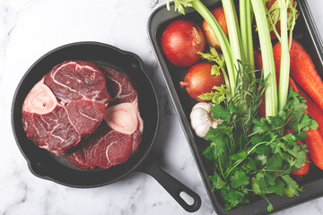 knuckle on the bone, raw meat for ossobuco, in a cast-iron pan, baking sheet with vegetables, top view, no people,